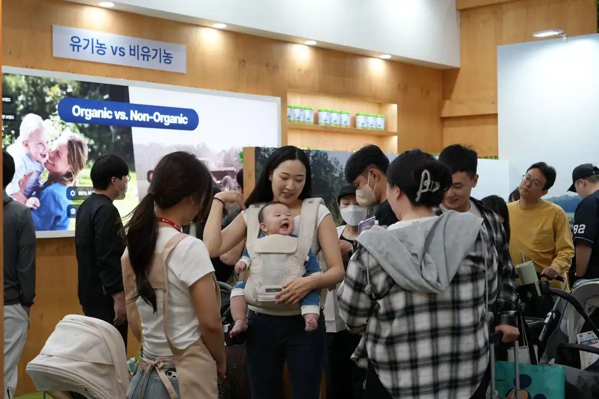 유기농 이유식 브랜드 부스에서 아이를 안고 상담받는 방문객